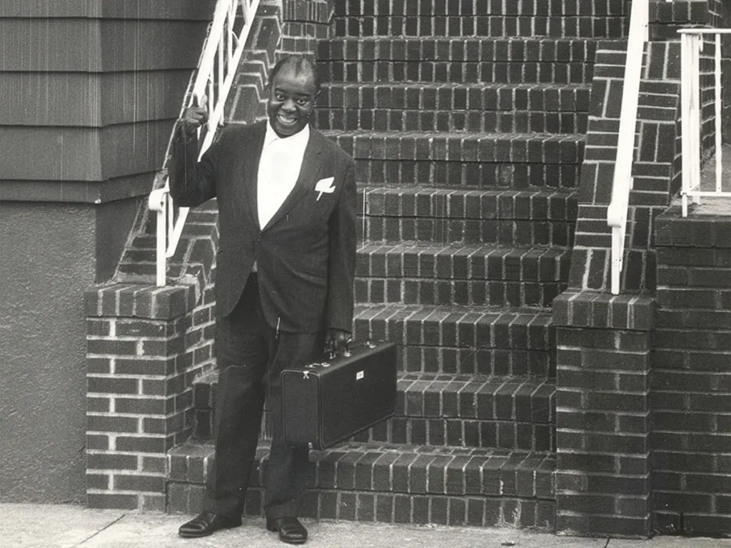Louis Armstrong in front of his home on 107th Street, Corona, Queens